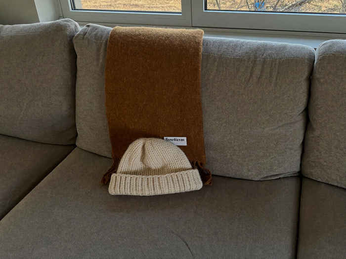 Wollschal und Strickmütze auf dem Sofa